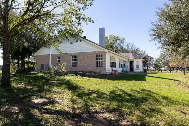 rear view of property featuring central air condition unit and a lawn