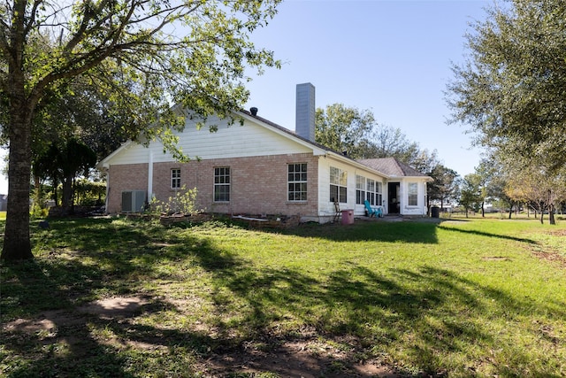 16004 Penick Rd, Waller, TX 77484 - rear view of property featuring brick siding, a chimney, and a lawn
