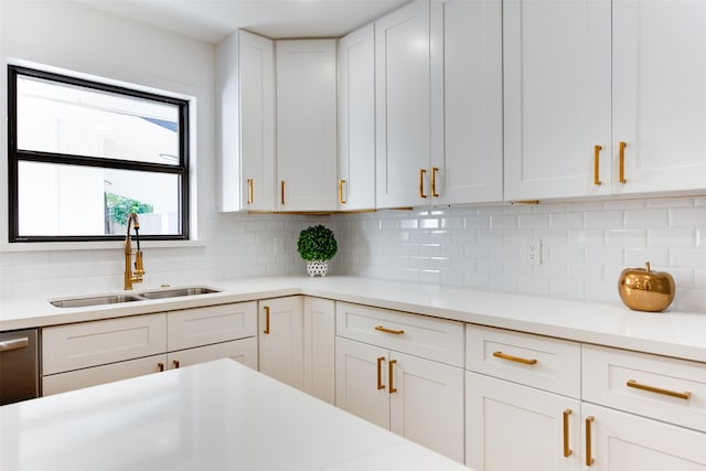 kitchen with backsplash, white cabinetry, and sink