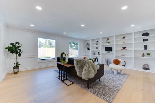 living room featuring built in features and light hardwood / wood-style flooring