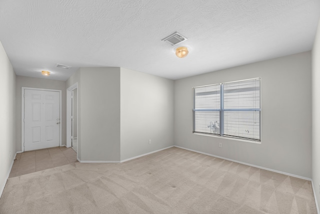 spare room with light carpet and a textured ceiling