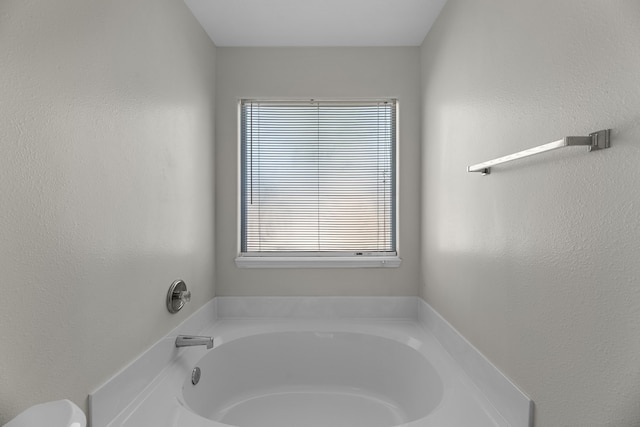 bathroom with a tub to relax in and plenty of natural light