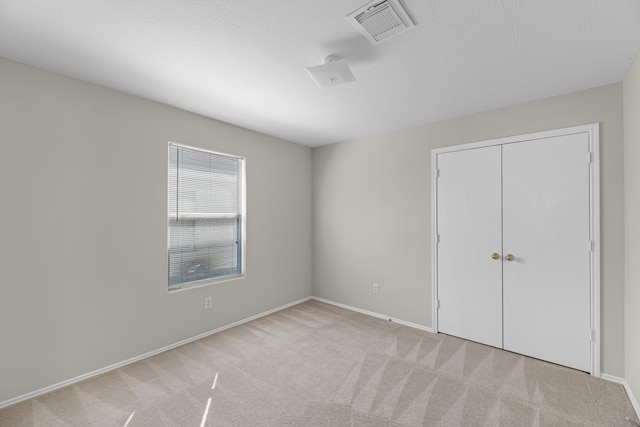 unfurnished bedroom featuring light colored carpet and a closet