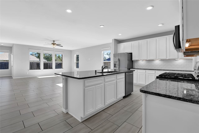 kitchen with a center island with sink, white cabinets, a healthy amount of sunlight, and appliances with stainless steel finishes