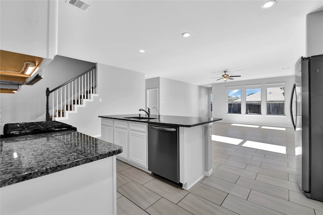 kitchen featuring appliances with stainless steel finishes, ceiling fan, a center island with sink, dark stone countertops, and white cabinets