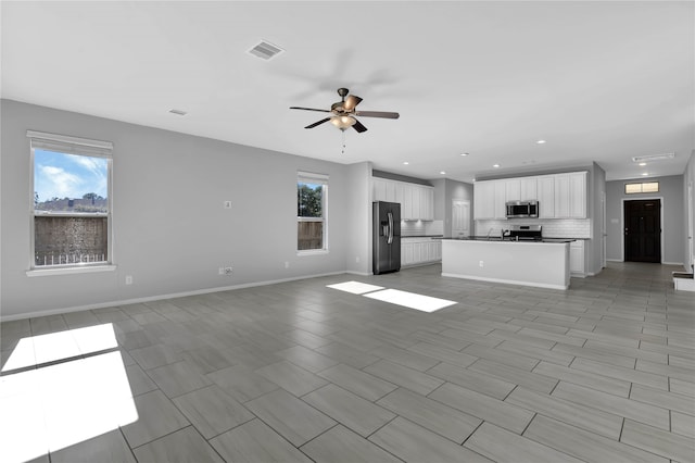 unfurnished living room with a wealth of natural light and ceiling fan