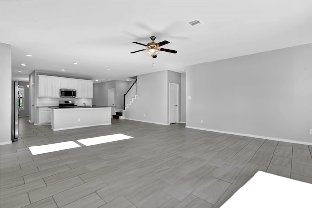 unfurnished living room featuring ceiling fan and sink