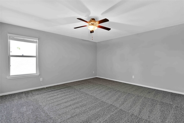 spare room featuring dark colored carpet and ceiling fan