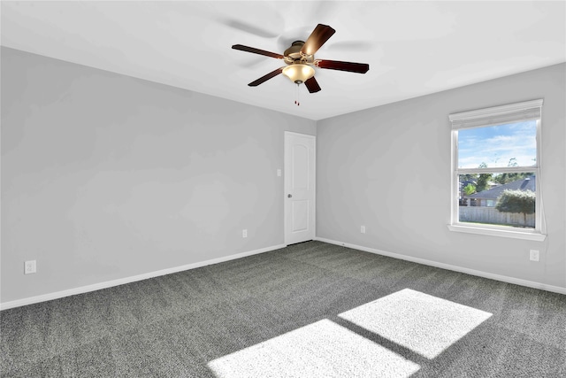 spare room featuring dark colored carpet and ceiling fan