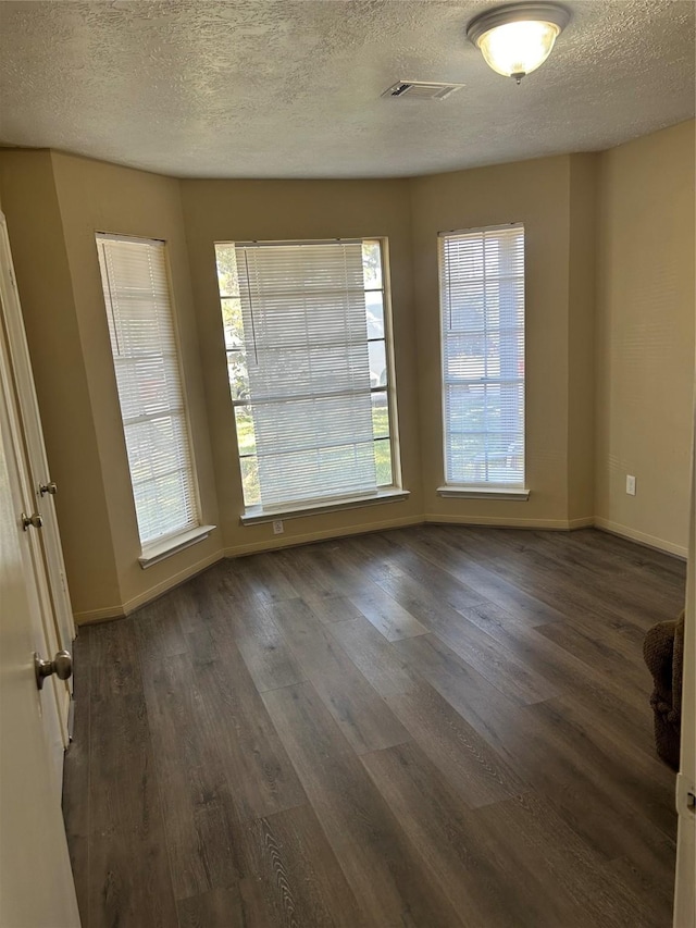 empty room featuring a textured ceiling and dark wood-type flooring