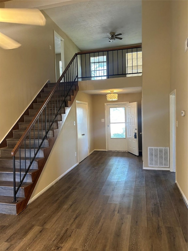 foyer entrance with a textured ceiling, ceiling fan, dark hardwood / wood-style flooring, and a high ceiling