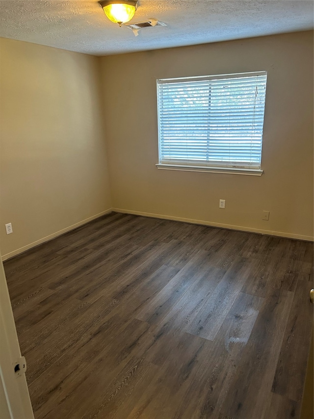 empty room featuring dark hardwood / wood-style flooring and a textured ceiling