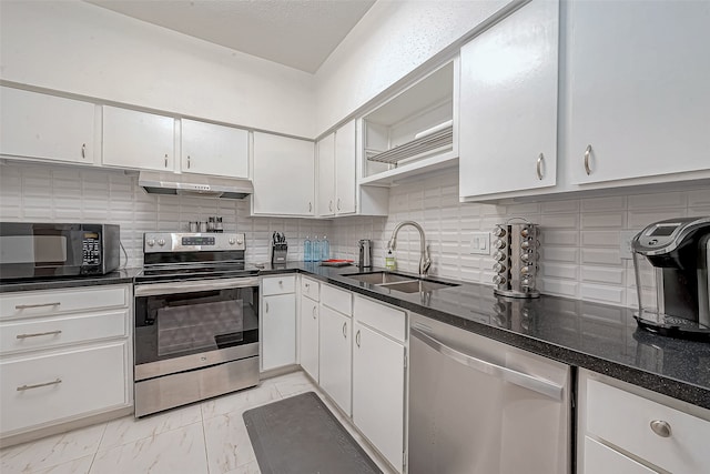 kitchen featuring sink, appliances with stainless steel finishes, dark stone counters, decorative backsplash, and white cabinets