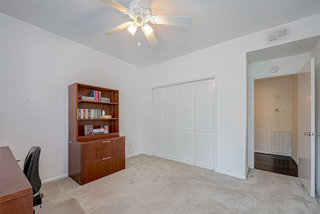 carpeted home office featuring ceiling fan