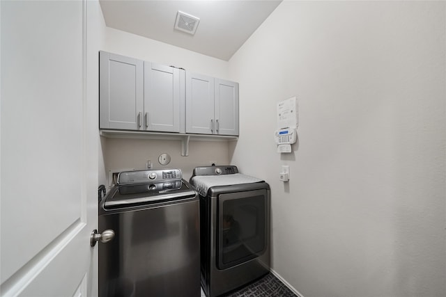 laundry room featuring washer and dryer and cabinets