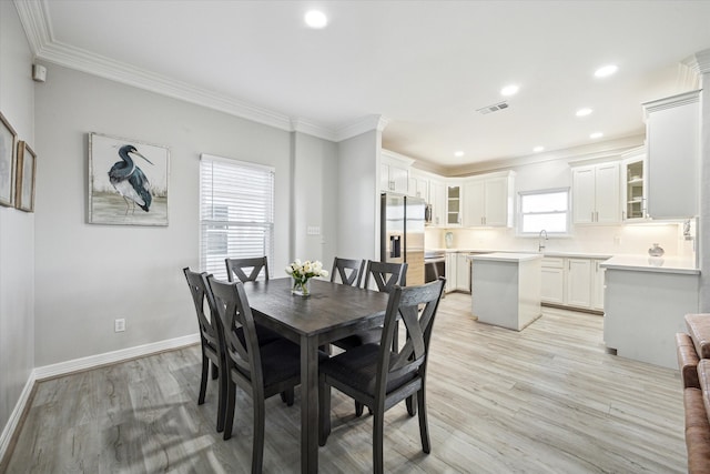 dining space with a healthy amount of sunlight, ornamental molding, sink, and light hardwood / wood-style flooring