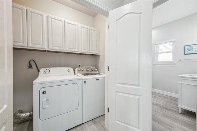 laundry room featuring washer and dryer, light hardwood / wood-style floors, and cabinets