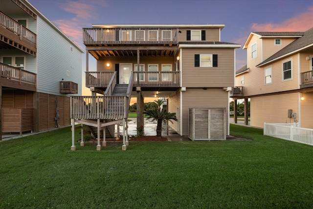 back house at dusk with a wooden deck and a lawn