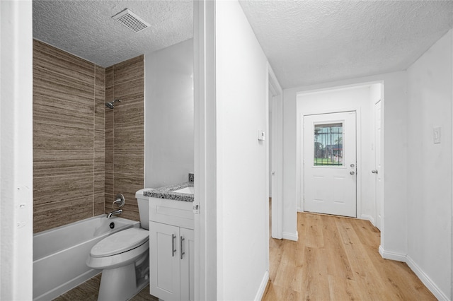 full bathroom with vanity, hardwood / wood-style floors, a textured ceiling, and tiled shower / bath combo