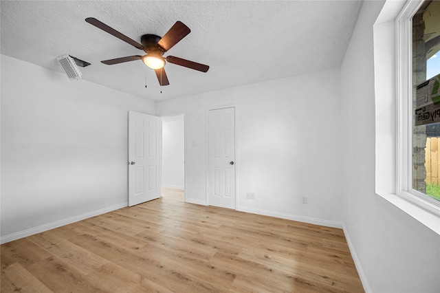 unfurnished room with a textured ceiling, light wood-type flooring, and ceiling fan