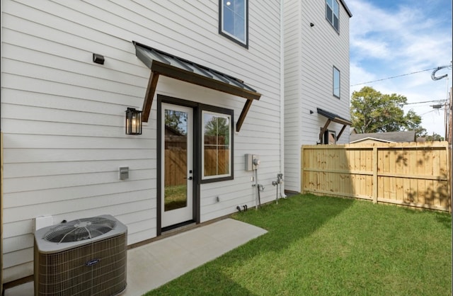 rear view of property with a lawn and cooling unit