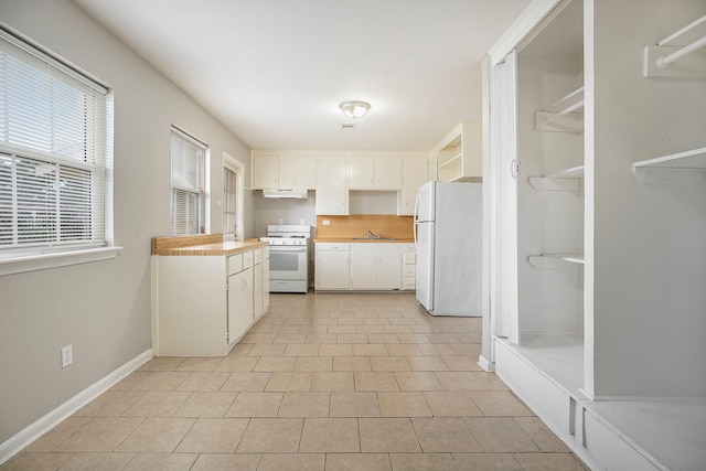 kitchen with white cabinets, light tile patterned floors, white appliances, and sink