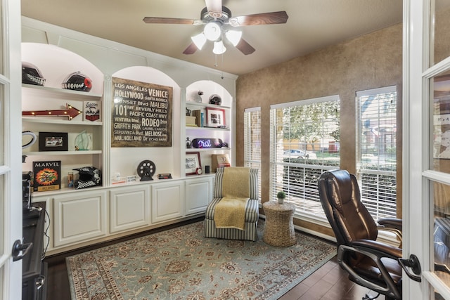 home office with built in features, ceiling fan, and dark wood-type flooring