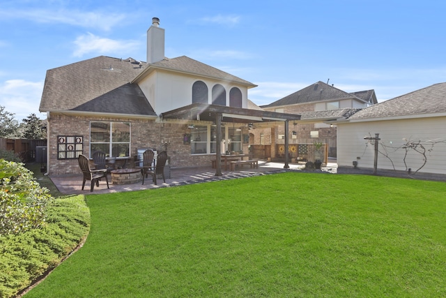 rear view of property featuring a yard, a patio, and an outdoor fire pit