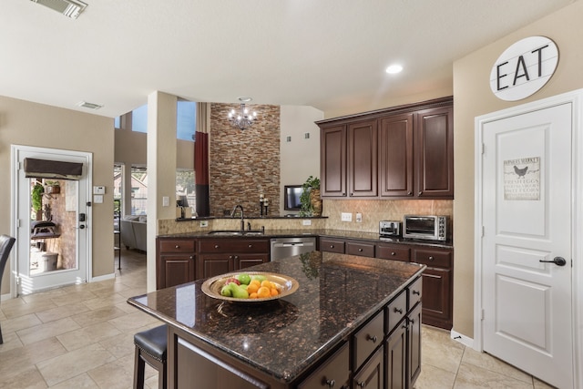 kitchen featuring dark brown cabinetry, sink, stainless steel dishwasher, decorative backsplash, and a kitchen island