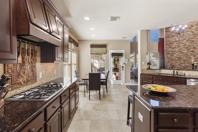 kitchen featuring a center island, backsplash, sink, dark brown cabinets, and stainless steel appliances