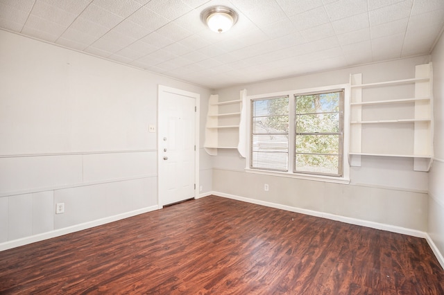 empty room featuring built in shelves and dark wood-type flooring