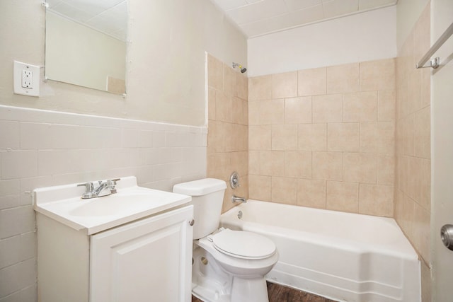 full bathroom with tiled shower / bath combo, toilet, vanity, tile walls, and hardwood / wood-style flooring