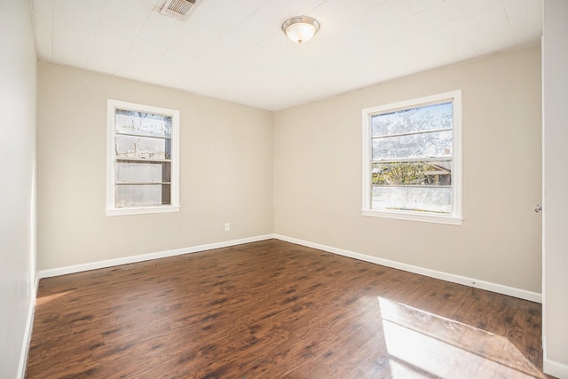 empty room featuring dark hardwood / wood-style flooring and plenty of natural light