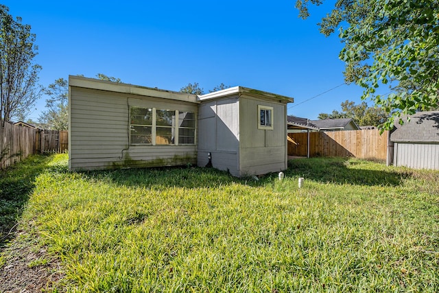 rear view of house featuring a yard and a shed