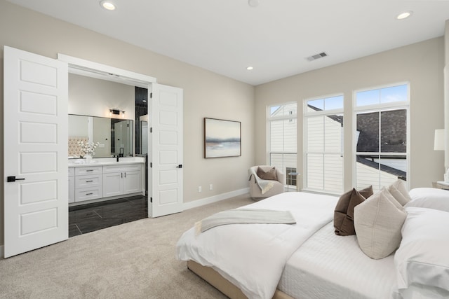 carpeted bedroom with ensuite bathroom and sink