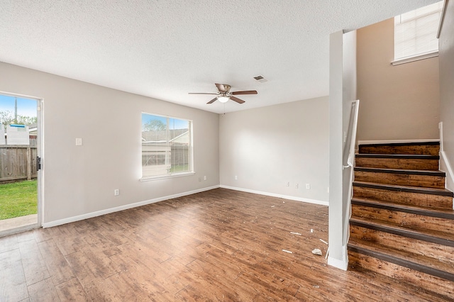 unfurnished living room featuring ceiling fan, wood-type flooring, and a textured ceiling