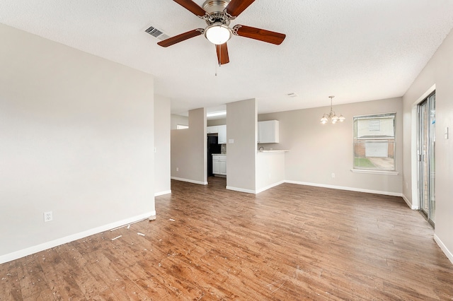 unfurnished living room featuring ceiling fan with notable chandelier, wood-type flooring, and a textured ceiling