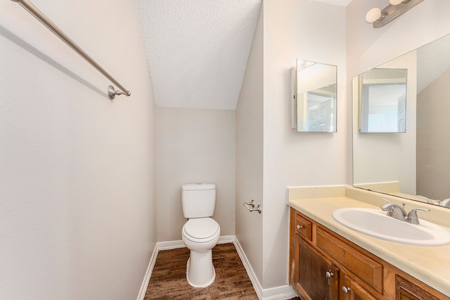 bathroom featuring vanity, a textured ceiling, vaulted ceiling, hardwood / wood-style floors, and toilet