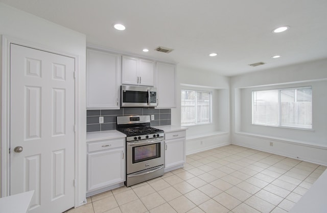 kitchen with decorative backsplash, white cabinetry, stainless steel appliances, and light tile patterned floors