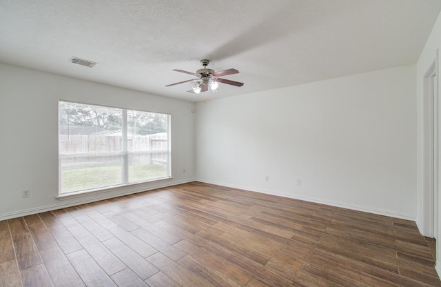 unfurnished room with a textured ceiling, ceiling fan, and dark wood-type flooring