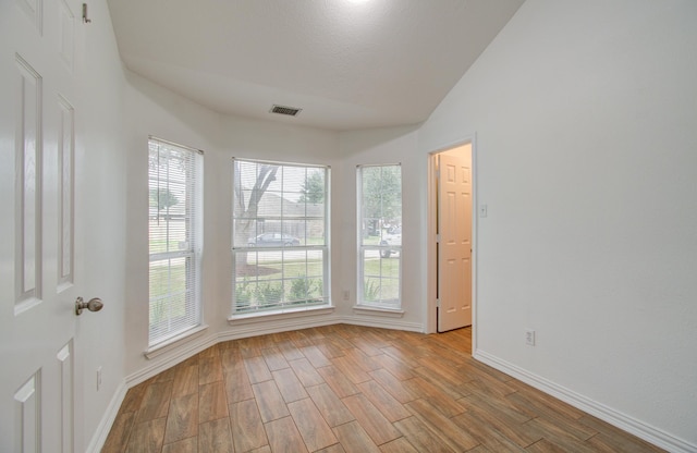 unfurnished room featuring lofted ceiling and light wood-type flooring