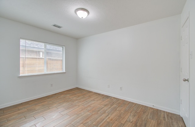 spare room with light hardwood / wood-style floors and a textured ceiling