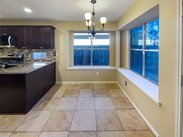 kitchen with an inviting chandelier, dark stone countertops, tasteful backsplash, decorative light fixtures, and stainless steel appliances