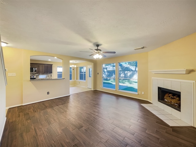 unfurnished living room with a textured ceiling, a tile fireplace, hardwood / wood-style floors, and ceiling fan with notable chandelier