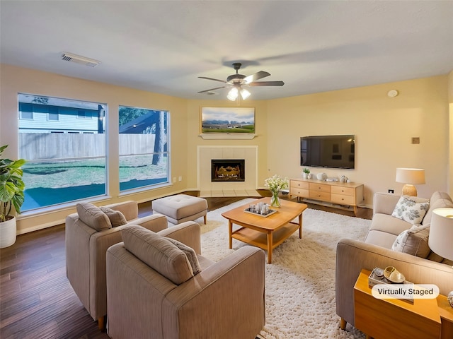 living room with a fireplace, ceiling fan, and dark wood-type flooring