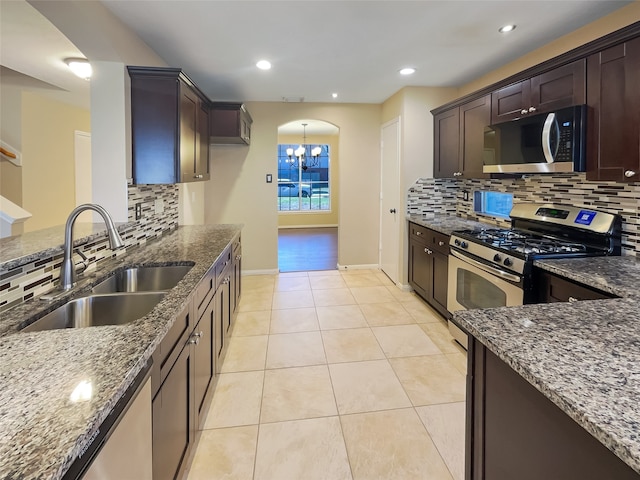 kitchen featuring dark stone counters, sink, decorative backsplash, a notable chandelier, and stainless steel appliances