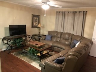 living room with dark hardwood / wood-style flooring and ceiling fan