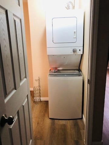 clothes washing area with dark hardwood / wood-style flooring and stacked washer and dryer