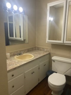 bathroom with hardwood / wood-style floors, vanity, and toilet