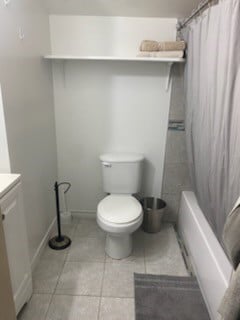 full bathroom featuring tile patterned floors, vanity, shower / bath combination with curtain, and toilet